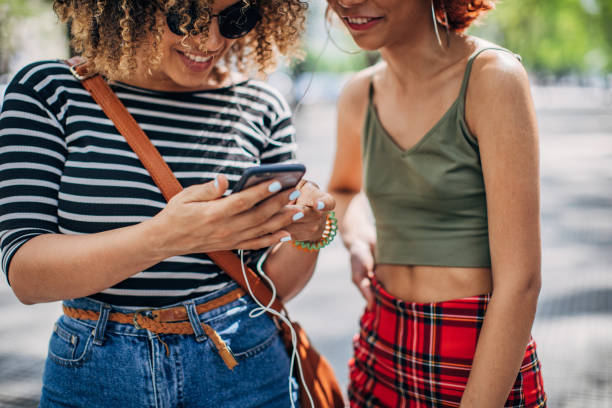 istock Two young women using phone outdoors 1192499173