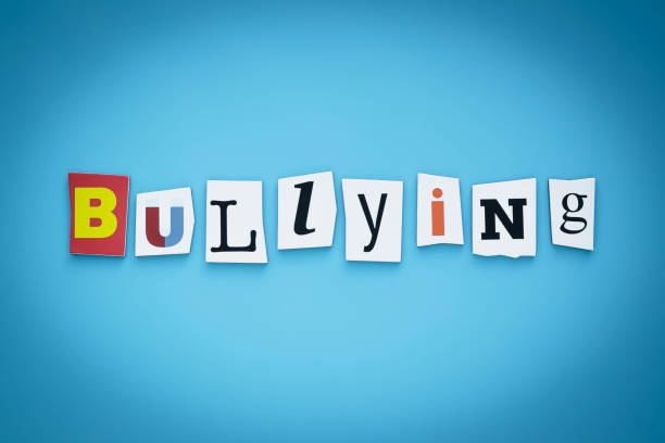 istock Text - bullying. Cut letters on blue background. Writing on banner, card. Inscription, message on poster. Single word. 1192499621
