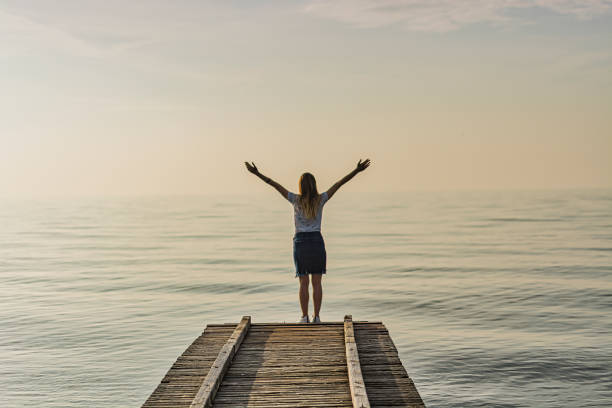 istock Woman Standing on a Ship Dock with Raised Arms 1192500469