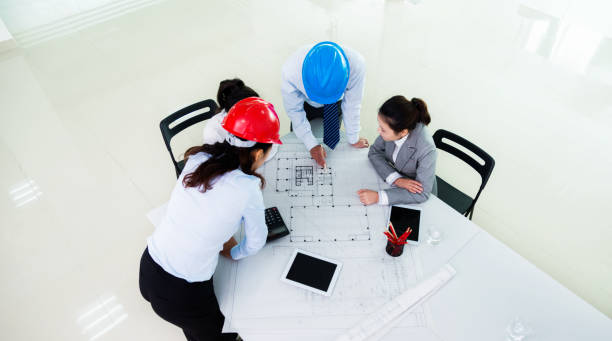 istock Group of architects and engineers discussing construction plans around a table 1192501236