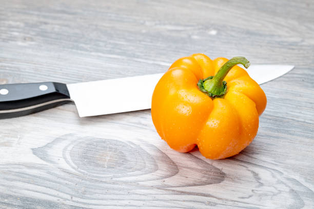 Unique orange bell pepper with a black handled knife