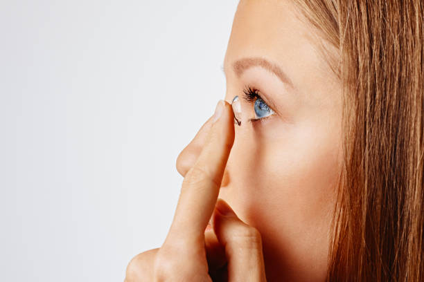 mujer joven pone lente de contacto en su ojo - human eye eyesight optometrist lens fotografías e imágenes de stock