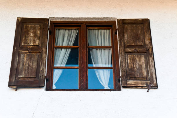 istock Old farmhouse window with shutters and curtains 1192508692