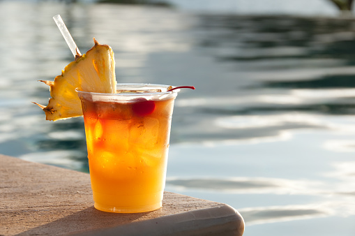 A tropical drink on the edge of a pool.