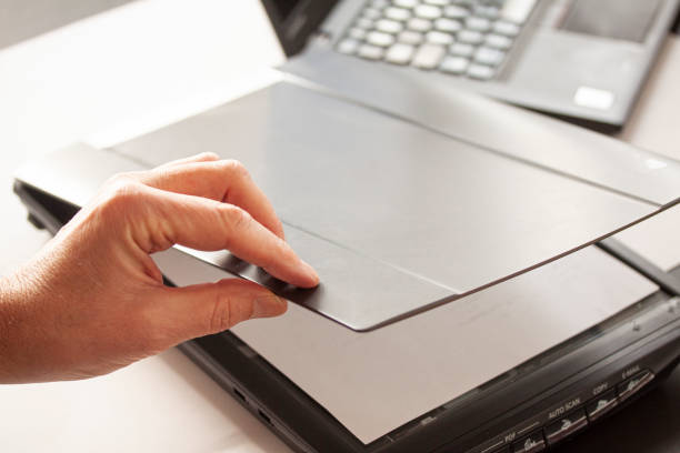 istock A hand closing a flatbed scanner with a laptop computer in the background. Selective focus image. 1192509698