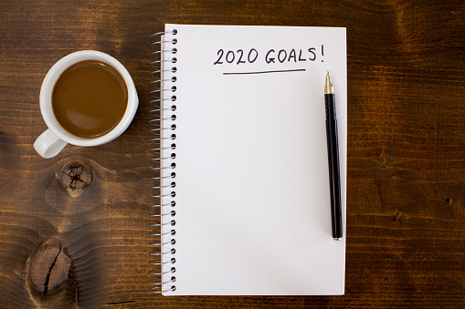 Coffee and notepad with 2020 Goals, on a wooden desk