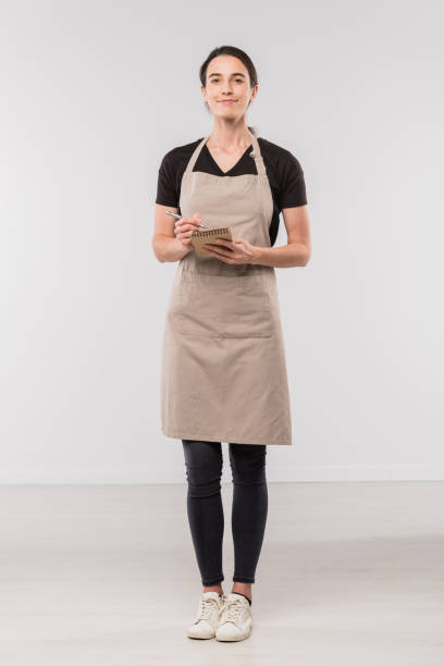 bastante morena camarera en ropa de trabajo haciendo notas en bloc de notas pequeño - uniforme de camarero fotografías e imágenes de stock