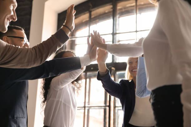 istock Overjoyed older and younger teammates joining hands in air. 1192516607