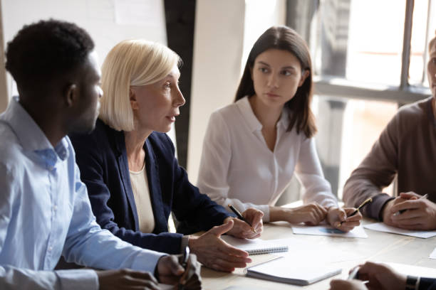 istock Confident older female boss team leader talking to focused workers. 1192516635