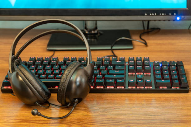 black backlit keyboard and headphones on a wooden table