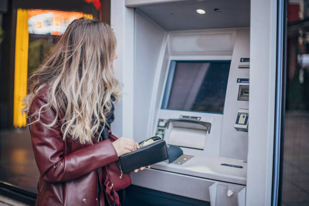 istock Fashionable young woman is using ATM 1192523177