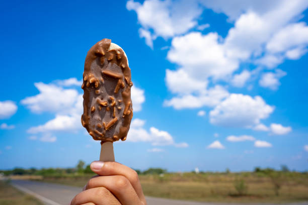 istock Ice crean on hand holding on blue sky and cloud background 1192525404