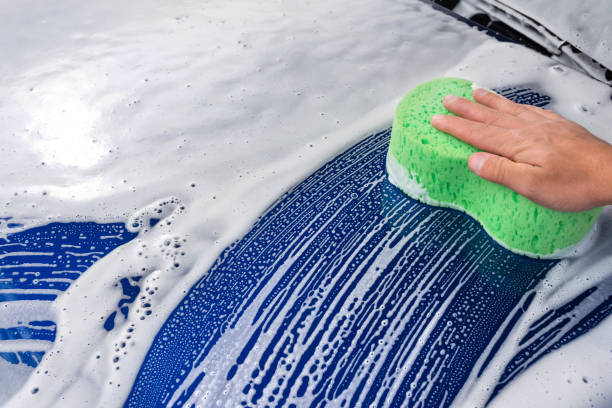 istock An washing a soapy blue car with a green sponge. 1192526591