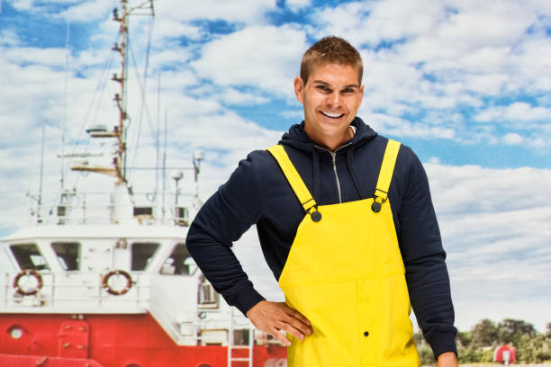 Waist up / one man only / one person of 20-29 years old adult handsome people caucasian male / young men standing who by the sea wearing hooded jacket / shirt / sweatshirt / bib overalls who is working with hand on hip / nautical vessel cintura para arriba / un hombre solamente / una persona de 20-29 años de edad adulto guapo personas caucásicas hombres / jóvenes de pie que por el mar usando chaqueta con capucha / camisa / sudadera / babero mono que está trabajando con la mano en la c