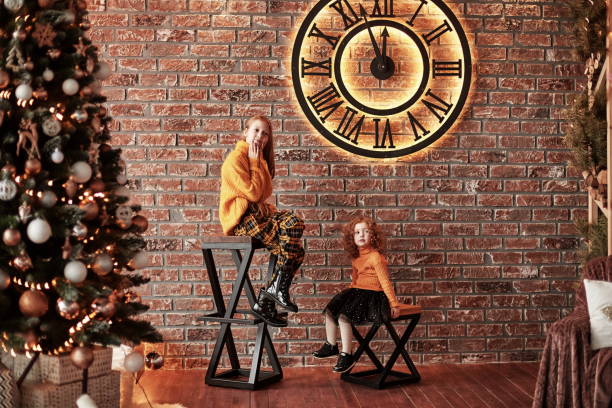 irmãs bonitas que sentam-se em uma sala de visitas à moda na véspera de natal - clock baby christmas small - fotografias e filmes do acervo