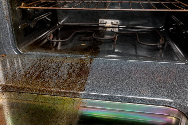 View inside electric oven with one half shiny clean and half filthy covered in burnt grease and food on glass and door. Housecleaning concept and comparison