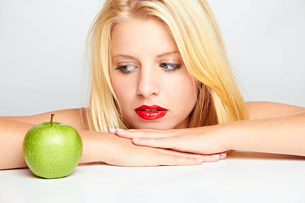 young blond woman with green apple stock photo