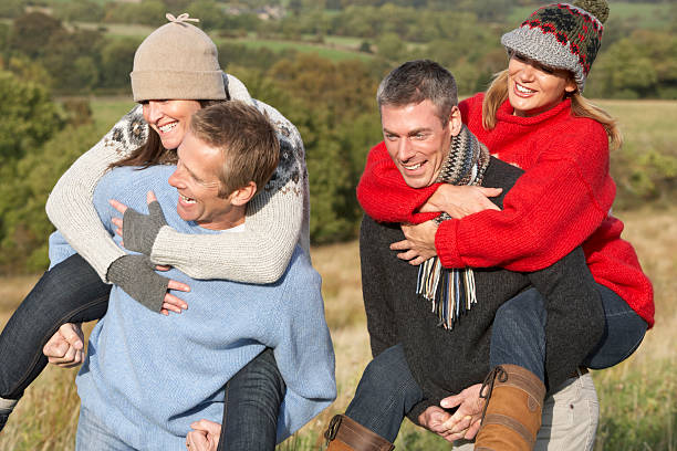 istock Two Couples Having Piggyback Ride In Autumn Landscape 119254373