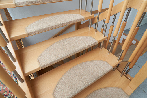 Steps of curved wooden staircase with anti-slip mat, close-up