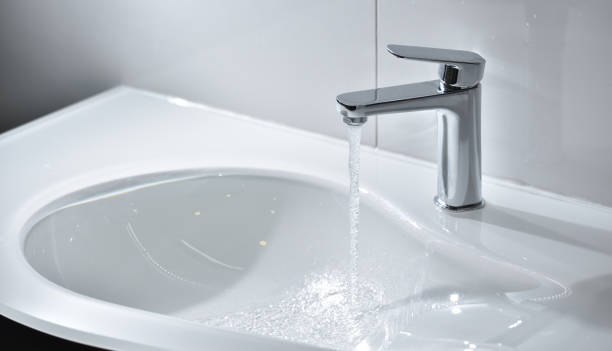 istock Chrome tap with open water that flows into a white modern sink 1192544422