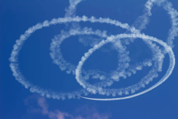 Abstract circular skywriting with a deep blue background This upward abstract view shows circular skywriting by an airplane with plumes of white vapor against a deep blue sky background. words in the sky stock pictures, royalty-free photos & images