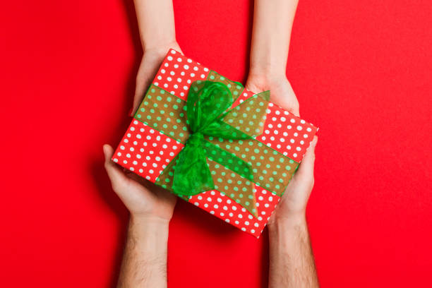 화려한 배경에 여성과 남성의 손에 선물을 들고의 상단보기. 여자와 남자는 선물을 주고 받는다. 복사 공간이 있는 휴일 컨셉시간 - gift ribbon straight wrapped 뉴스 사진 이미지