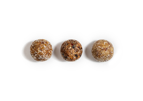 Homemade energy balls with dried apricots, raisins, dates, prunes, walnuts, almonds and coconut. Healthy sweet food. Energy balls on a white background. Flat lay, top view.