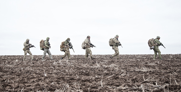 Soldados del ejército en marcha en el campo fangoso photo