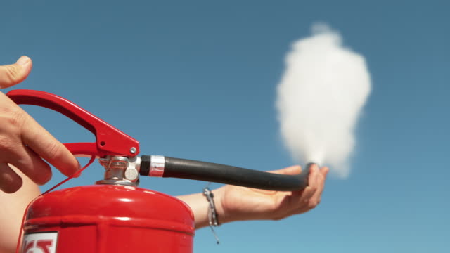 CLOSE UP: Unrecognizable person squeeze the handle of a fire extinguisher.