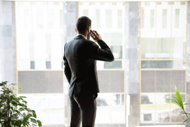 istock Successful young businessman talking on cellphone near windows 1192578943