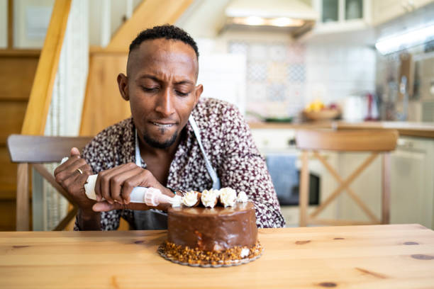 istock African man decorating birthday cake at home, making faces 1192579086