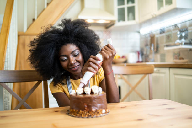istock Smiling african woman preparing cake at home, decorating 1192579089
