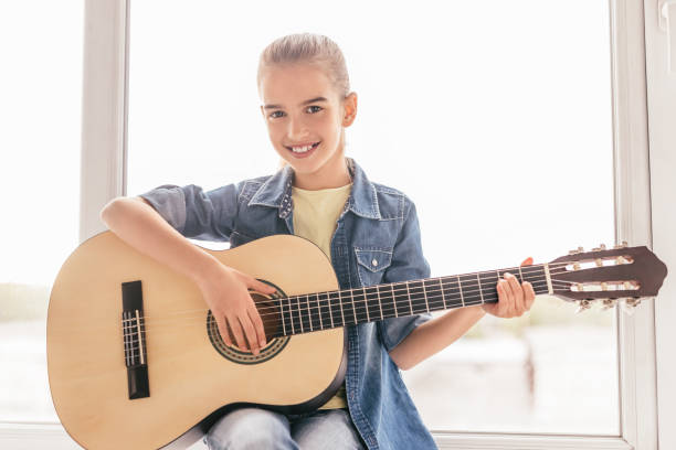 istock Smiling child playing guitar near window 1192579147
