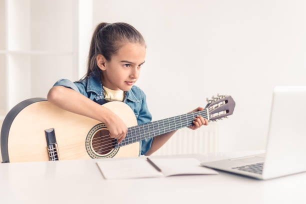 온라인으로 기타를 연주하는 법을 배우는 어린 소녀 - guitar child music learning 뉴스 사진 이미지