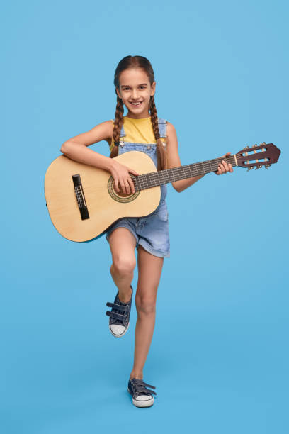 istock Smiling girl playing guitar and looking at camera 1192579170
