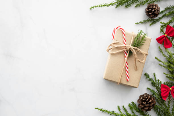 istock White marble table with Christmas decoration including gift box, candy cane, pine branches and pine cones. Merry Christmas and happy new year concept. Top view with copy space, flat lay. 1192603006