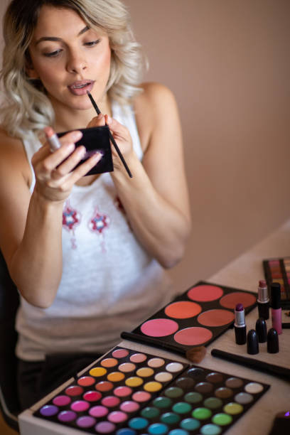 istock Beautiful young woman applying lipstick 1192605474