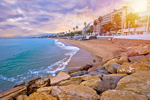 Cannes. Idyllic palm waterfront and sand beach in Cannes sun haze view, famous tourist destination of French riviera, Alpes Maritimes region of France
