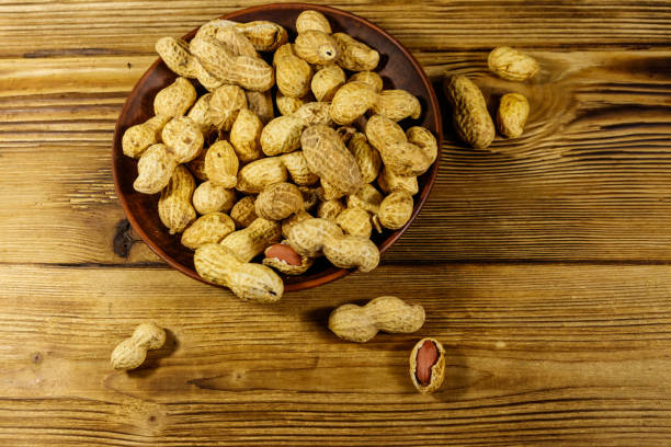 istock Peanuts in nutshell on a wooden table. Top view 1192607884