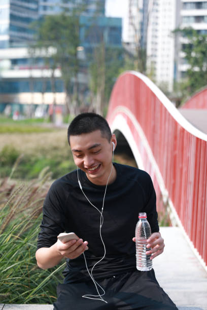 istock A smiling young Chinese man looking at his phone while doing exercise in a park 1192615306