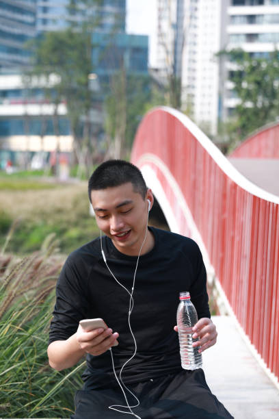 istock A smiling young Chinese man looking at his phone while doing exercise in a park 1192615308