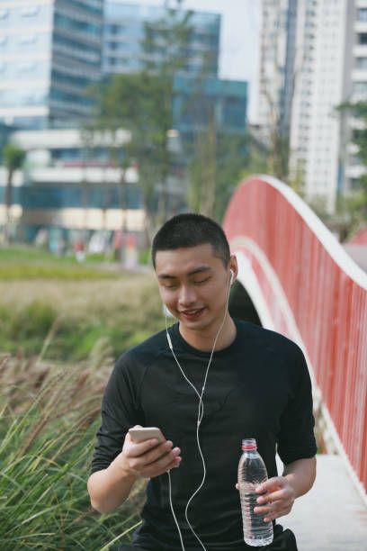 istock A smiling young Chinese man looking at his phone while doing exercise in a park 1192615363
