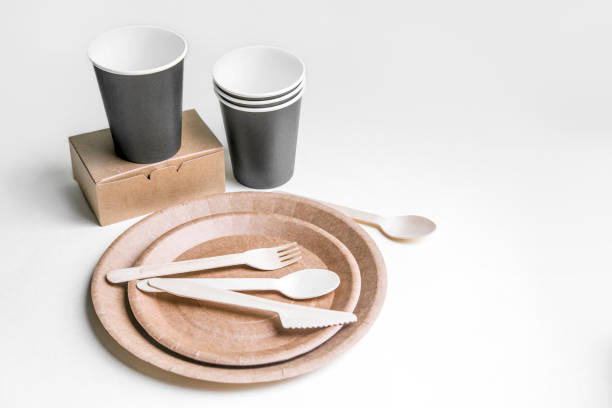 istock eco friendly disposable dishes made paper on white marble background. Draped spoons, fork, knives, plate with paper cups. recycling concept 1192621800