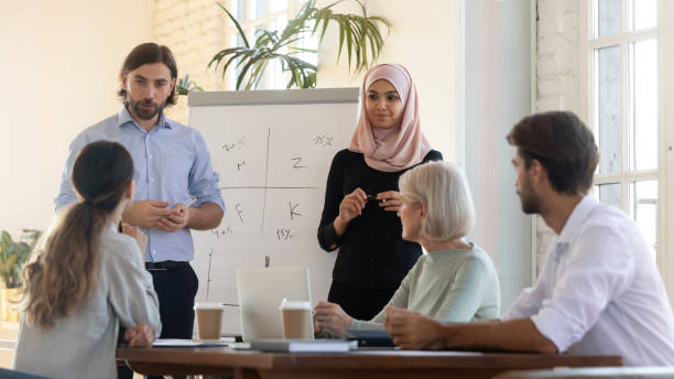 istock Focused mixed race speakers presenting project ideas near flipchart. 1192624588