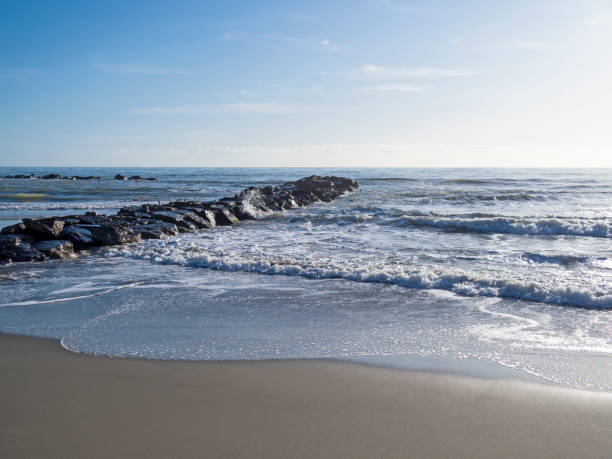istock Sandy beach with breaking waves and rocky jetty. Mediterranean Sea, Europe. 1192625738
