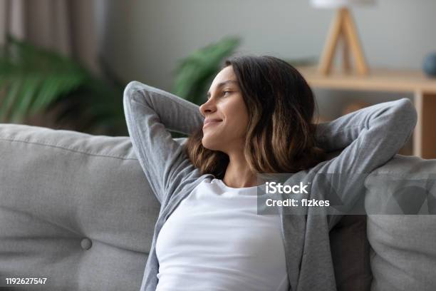Woman Put Hands Behind Head Leaned On Couch Resting Indoors Stock Photo - Download Image Now