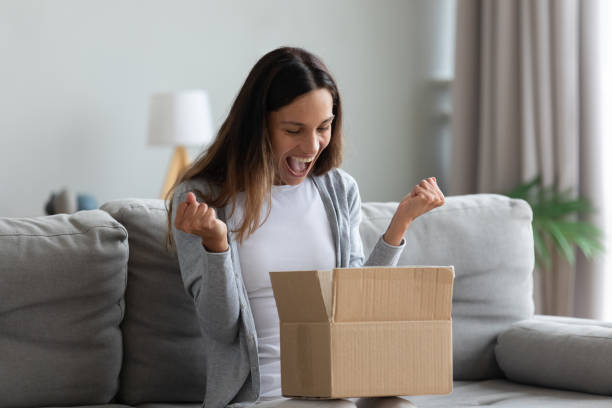 Woman screaming with joy opens carton parcel box feels happy Woman sit on couch screaming with joy opens carton box feel happy, addressee girl received long-awaited package, fast easy and quick post mail parcel delivery, reliable postal courier service concept buy new things stock pictures, royalty-free photos & images