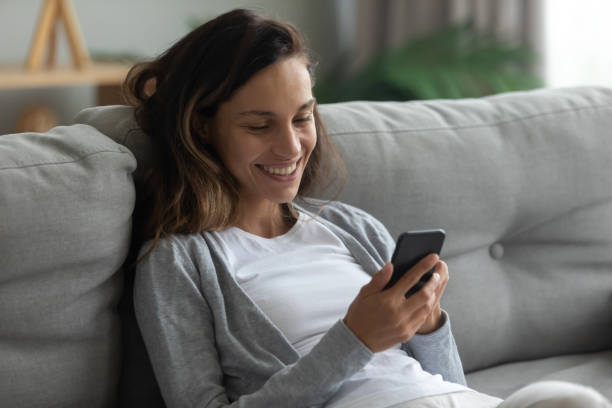 istock Woman leaned on sofa enjoy lazy weekend with smartphone 1192627579