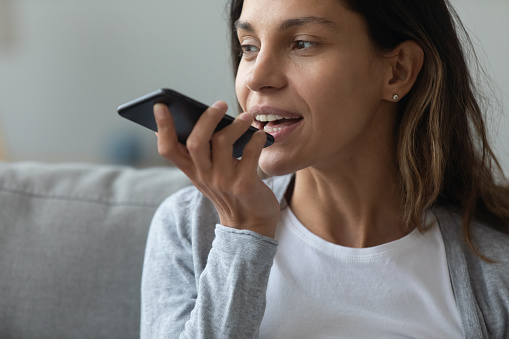 Close up of pretty woman holding in hand smart phone talking with digital assistant or friend distantly uses easy voice messaging, concept of modern ai technology, voice recognition, online translator