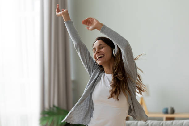 mujer con auriculares bailando en la sala de estar en casa - chill out audio fotografías e imágenes de stock